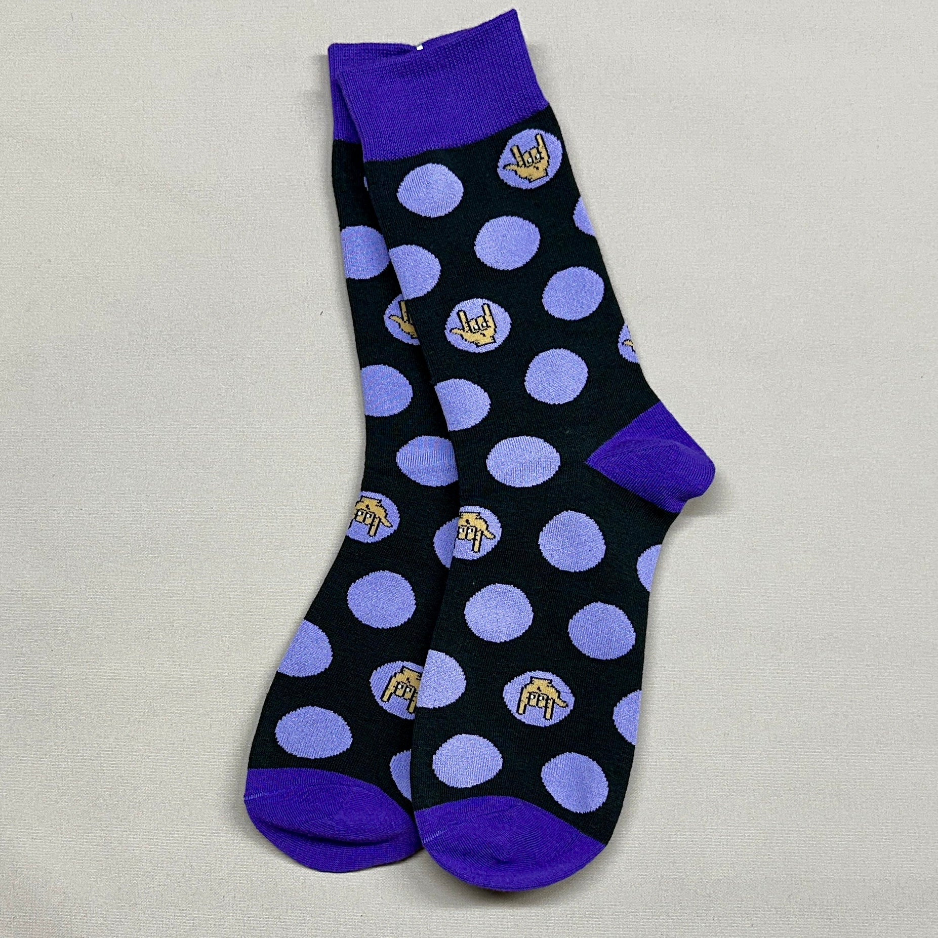 Black socks with purple dots and small logos on a light gray background