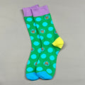 Green socks with blue polka dots and purple cuffs on a gray background