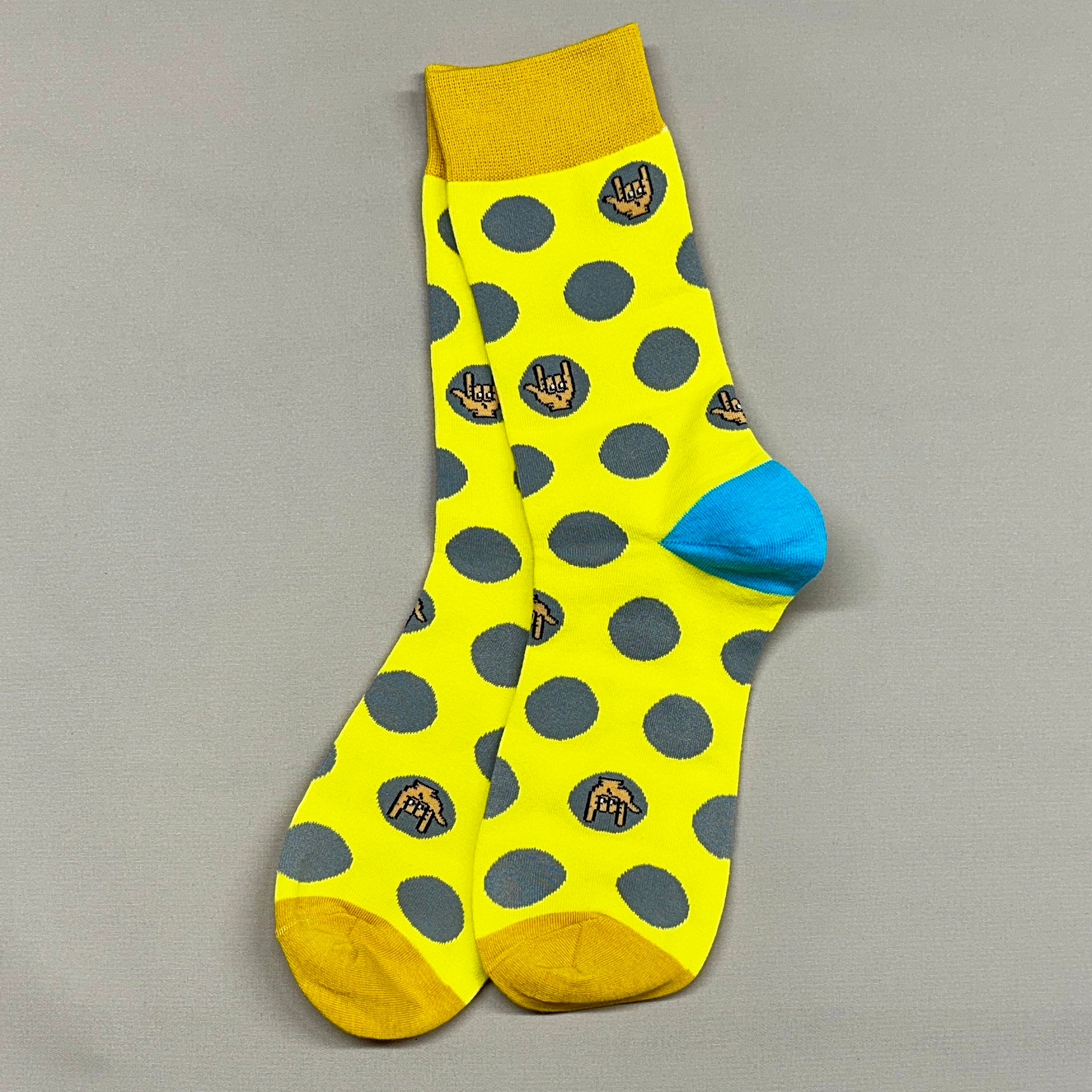 Yellow sock with gray polka dots and blue heel on a gray background